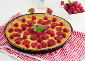 Round quiche with red strawberries and raspberries on a white table, top view