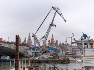 MOSCOW, RUSSIA - May 01, 2021: construction crane with an extended boom near the Big Stone Bridge over the Moscow River, against the background of the Kremlin Hill