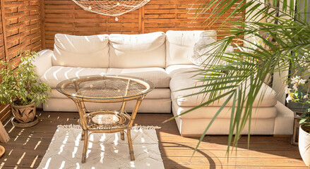 Real photo of relaxing boho zone in home. Wooden floor on terrace with comfy furniture and green plants. Decoration concept.