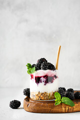 Blackberry granola yogurt dessert with berris and mint leaf on wooden cut borad