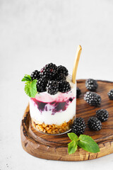 Blackberry granola yogurt dessert with berris and mint leaf on wooden cut borad