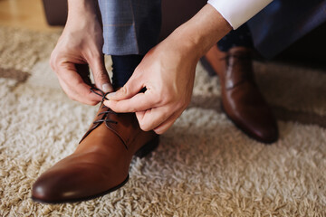 Brown leather shoe lacing. Businessman in white shirt and suit trousers. Groom getting ready for...