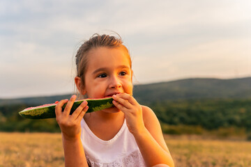 Young mother with children outdoor. Cute little caucasian girls and their mother eating watermelon outdoor at hot summer day. Kids siblings spending time together and having fun during summer.