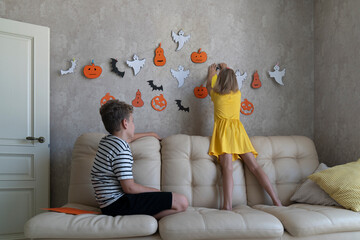 Children hang a garland for the Halloween party on the wall.