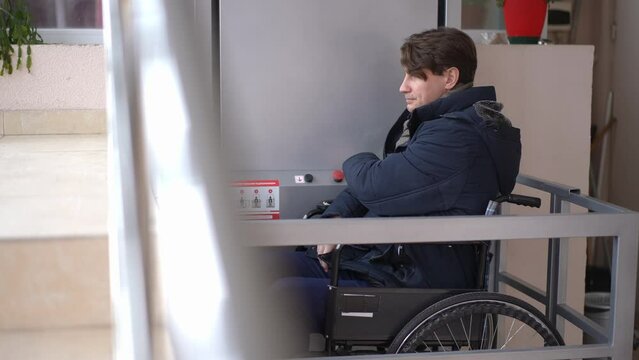 Live camera follows man in wheelchair pushing button moving up on elevator in hospital. Side view portrait of Caucasian guy using accessibility lift indoors. Lifestyle and service
