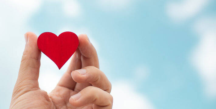 heart in hand on blue sky background 