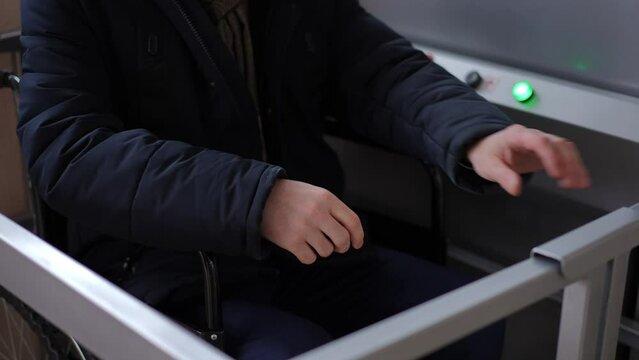 Elevator platform for people with disabilities moving down and unrecognizable Caucasian man opening barrier. Ill guy sitting on wheelchair using lift indoors in building