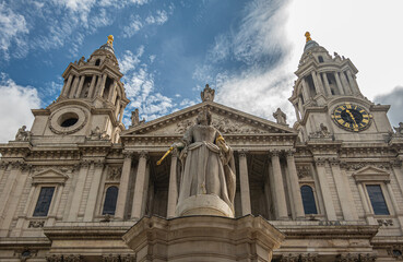 London, England, UK - July 6, 2022: St. Paul's Cathedral. Statue of Queen Anne on West churchyard with the 2 towers and facade pediment in back under blue cloudscape.