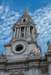 Fototapeta na wymiar London, England, UK - July 6, 2022: St. Paul's Cathedral. Closeup of NW tower spire with golden top and no clock. Stone statues on corners and above under blue cloudscape.