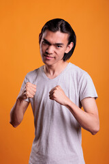 Angry strong young asian man standing in fighting pose with serious facial expression. Furious teen...