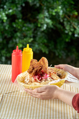 Pollo firto con tajadas servido en una canasta de plastico