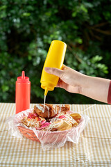 Agregando salsa al  Pollo firto con tajadas servido en una canasta de plastico