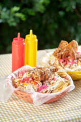 Pollo firto con tajadas servido en una canasta de plastico