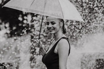 Happy woman having fun at the city fountain on a summer day with a transparent umbrella.