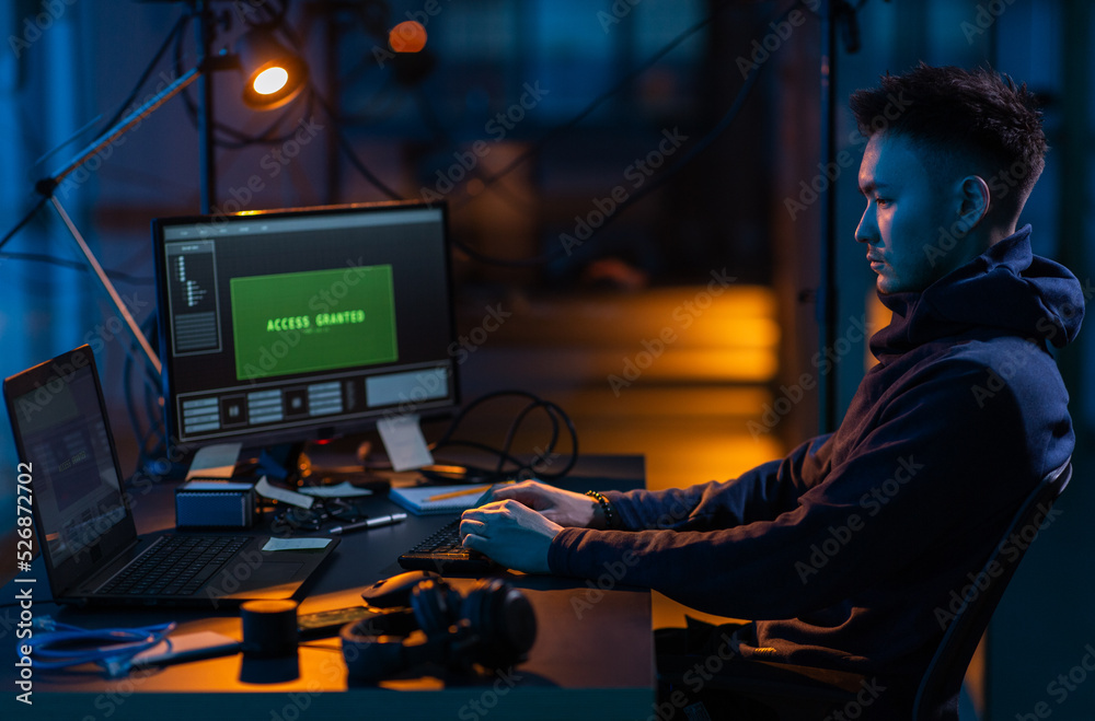 Poster cybercrime, hacking and technology concept - male hacker in dark room writing code or using computer