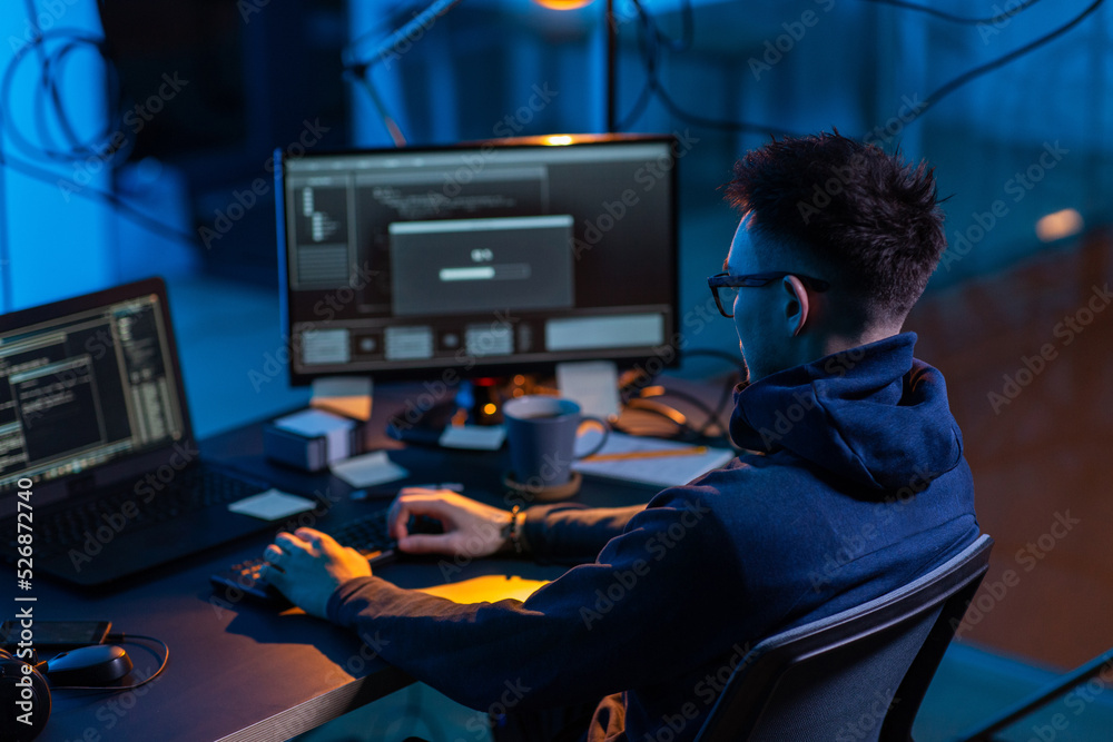 Poster cybercrime, hacking and technology concept - male hacker in dark room writing code or using computer