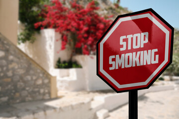 Sign Stop Smoking on city street, space for text