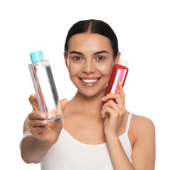 Young woman with bottles of micellar water on white background