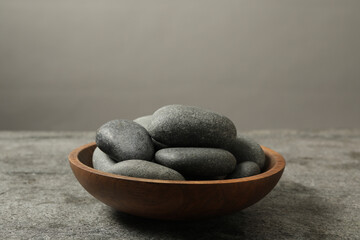Bowl with spa stones on grey table, closeup