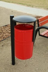 Fototapeta na wymiar Red metal trash bin on city park