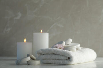 Fototapeta na wymiar Spa stones, towel and burning candles on white table