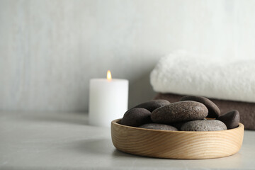 Spa stones in wooden tray on light table. Space for text
