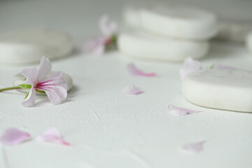 Obraz na płótnie Canvas Spa stones and fresia flower on white table, closeup