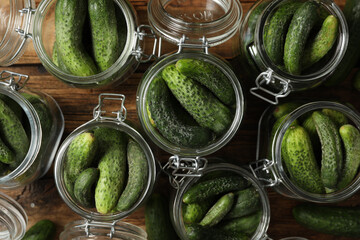 Fototapeta Pickling jars with fresh cucumbers on wooden table, flat lay obraz