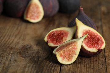 Whole and cut tasty fresh figs on wooden table, closeup. Space for text