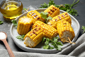 Delicious grilled corn cobs on grey table