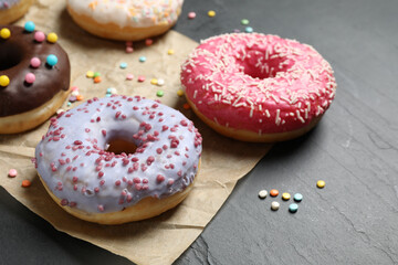 Yummy donuts with sprinkles on dark background, closeup