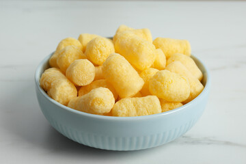 Bowl of delicious crispy corn sticks on white marble table