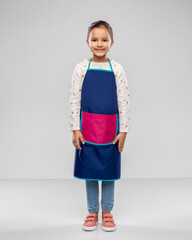Fototapeta premium cooking, culinary and profession concept - happy smiling little girl in kitchen apron over grey background