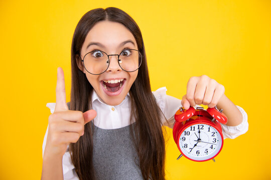 Portrait of teenage girl with clock alrm, time and deadline. Studio shot isolated on yellow background. Surprised teenager girl.