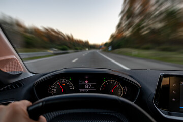 Driver view to the speedometer at 87 kmh or 87 mph and the road blurred in motion, night fall view...