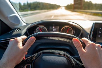 Car steering wheel holded by two hands, on a highway road