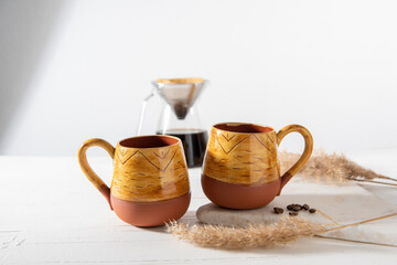 Obraz na płótnie Canvas ceramic coffee cups with coffee drip on the table