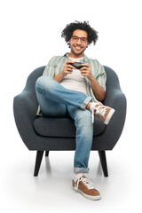 technology, people and leisure concept - happy smiling young man in glasses with gamepad sitting in...