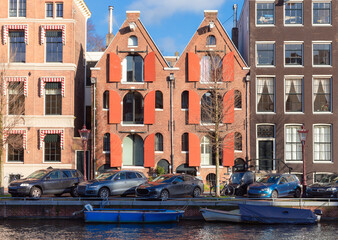 Beautiful old houses on the city waterfront of Amsterdam on a sunny day.