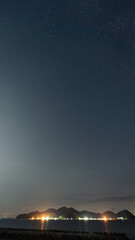 海岸で撮られた星空と対岸の灯火