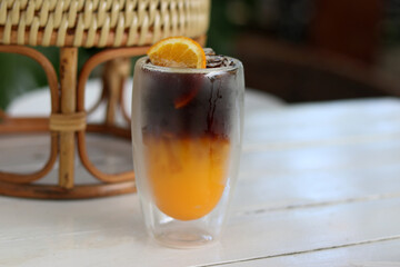 Coffee and orange topping with sliced orange on wooden background. This menu is very popular in Thailand called Black Orange Coffee while in Japan called Yuzu Orange Coffee.