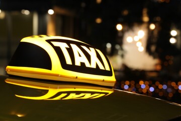 Taxi car with yellow sign outdoors at night, closeup