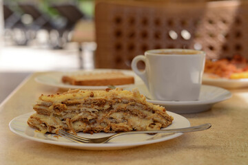Piece of delicious cake and coffee on beige table in cafe, closeup
