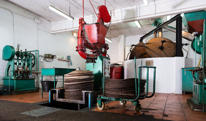 Interior of small olive oil producing factory with machine for applying olive paste on fiber mats...