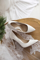 Pair of white high heel shoes, veil and wreath on wooden chair indoors, above view. Dressing for wedding