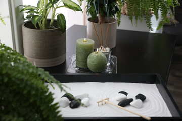 Candles and incense sticks near miniature zen garden on black table