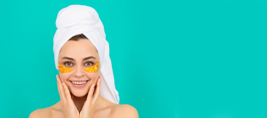 cheerful young lady has collagen golden eye patches on face with towel. Beautiful woman isolated...