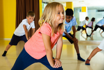 Cute preteen girl exercising with group of children in choreography class.