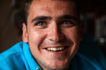 Defocus 20s smiling man. Closeup portrait of a happy young man smiling on blurred background. Face young man with funny kind eyes and smile. Out of focus