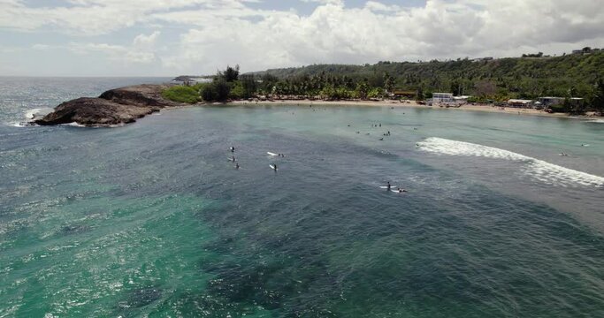 Aerial view of surfers in shallow waters of Isabela, Puerto Rico, USA - circling, drone shot